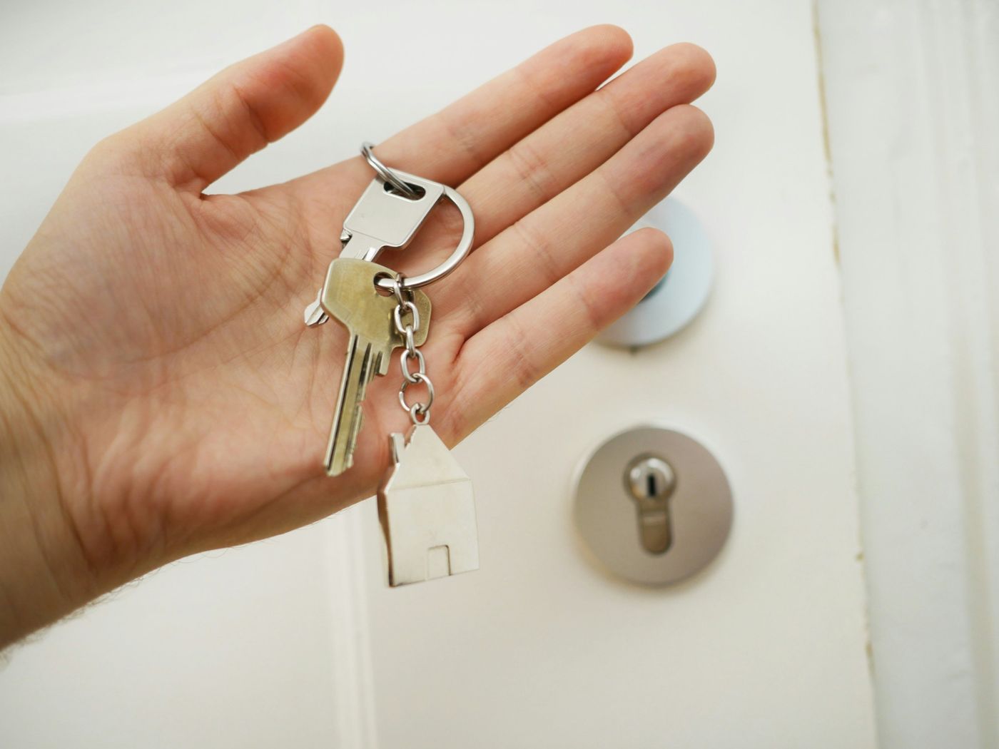 Hand holding house keys in front of a front door